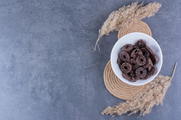 Petit-déjeuner sain avec des anneaux de maïs au chocolat dans une assiette sur une surface en pierre