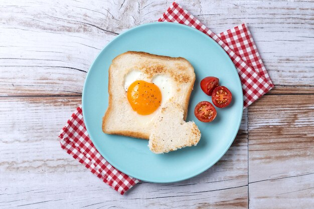 Photo gratuite petit-déjeuner de saint valentin avec œuf aux tomates en forme de coeur et pain grillé sur tablexa en bois