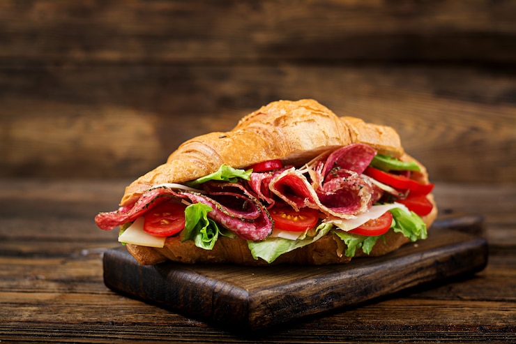 Photo gratuit petit déjeuner savoureux. croissant appétissant au salami et au fromage et aux tomates