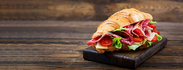 Petit déjeuner savoureux. Croissant appétissant au salami et au fromage et aux tomates