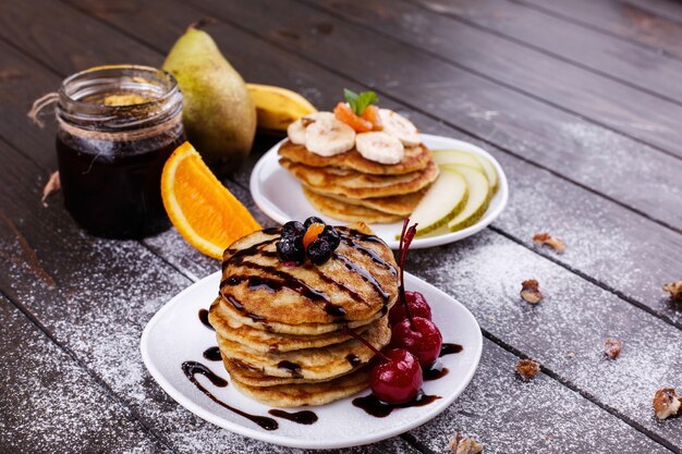 Petit-déjeuner savoureux. Délicieuses crêpes recouvertes de chocolat, de cerises, de bananes et de poires