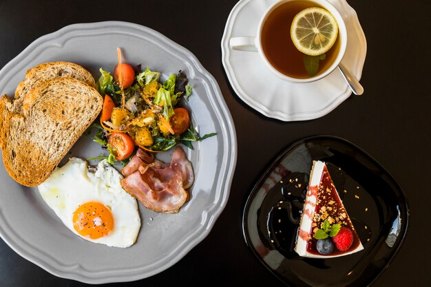 Petit déjeuner; thé au citron; gâteau au fromage aux baies o fond noir