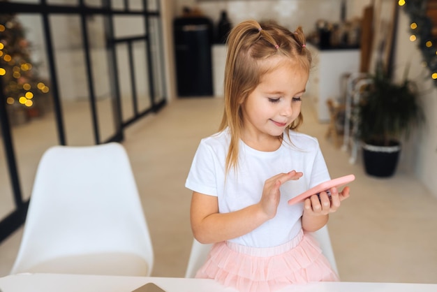 Petit enfant assis au bureau avec un ordinateur portable tenir un téléphone portable