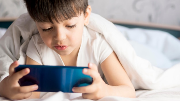 Photo gratuite petit enfant au téléphone avec lit