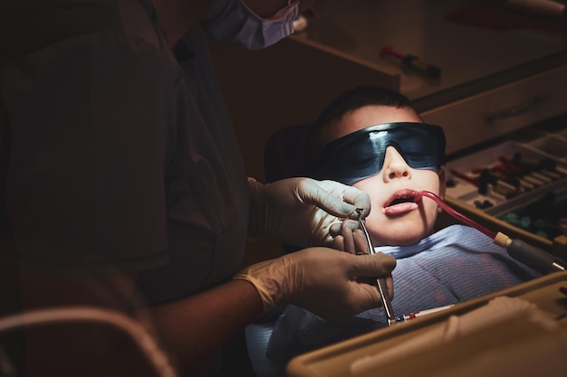 Un petit enfant courageux reçoit un traitement dentaire par un médecin expérimenté à la clinique dentaire.