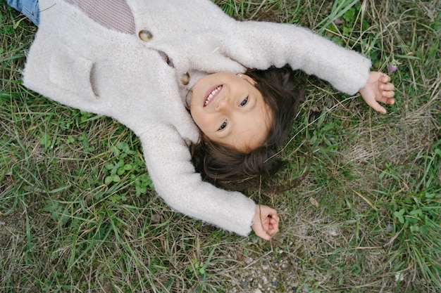 Petit enfant dans un joli pull blanc. Fille passer du temps dans un parc