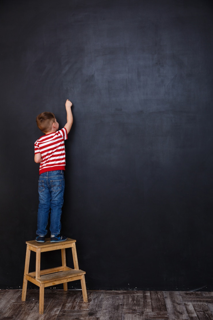 Photo gratuit petit enfant debout sur une chaise et dessin