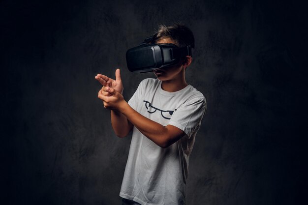 Un petit enfant à la mode joue à un nouveau jeu vidéo de tir à l'aide de lunettes de réalité virtuelle spéciales.