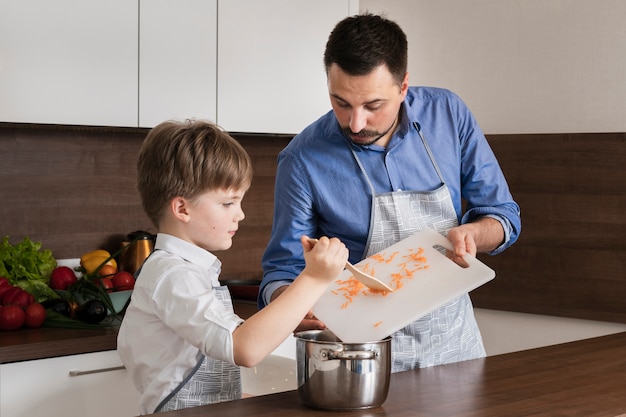 Petit fils à angle élevé aidant papa à cuisiner