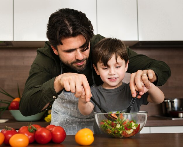 Petit garçon aide papa à mélanger la salade