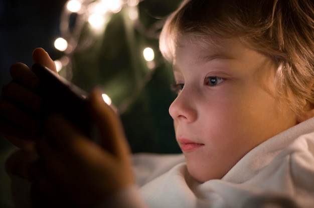 Petit garçon à l'aide de smartphone au lit la nuit