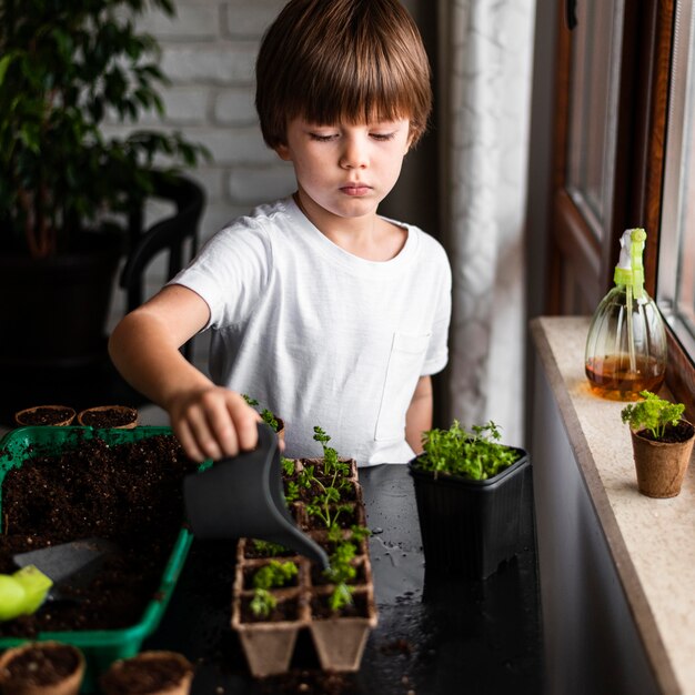 Petit garçon arrosant les cultures à la maison