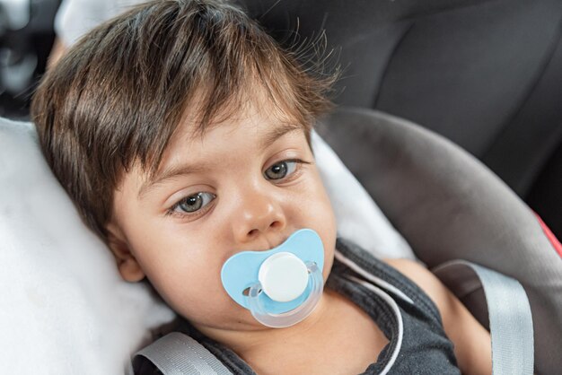 Petit garçon aux yeux bleus assis dans le siège bébé