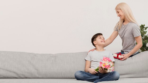 Petit garçon sur un canapé avec des cadeaux pour maman