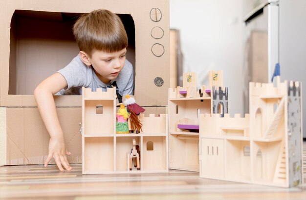 Photo gratuite petit garçon avec château en bois