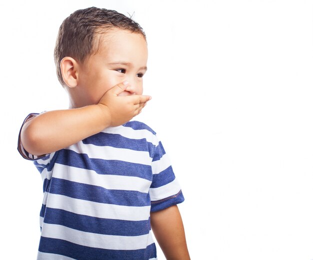 Petit garçon couvrant sa bouche en riant