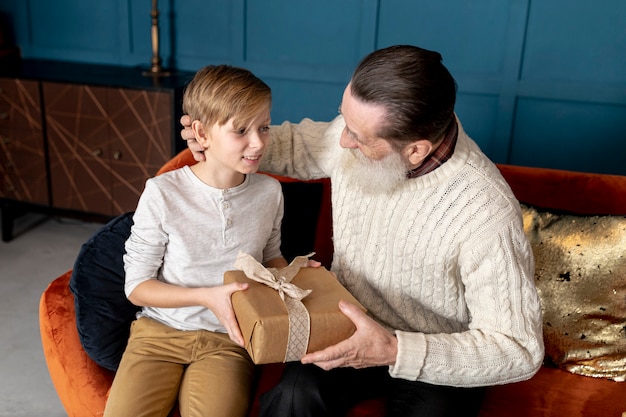 Photo gratuite petit garçon donnant un cadeau à son grand-père