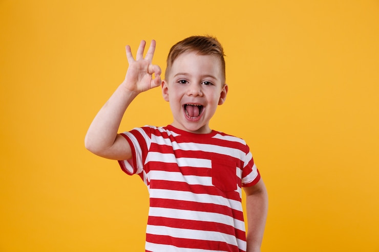 Photo gratuit petit garçon excité debout et montrant un geste d'accord