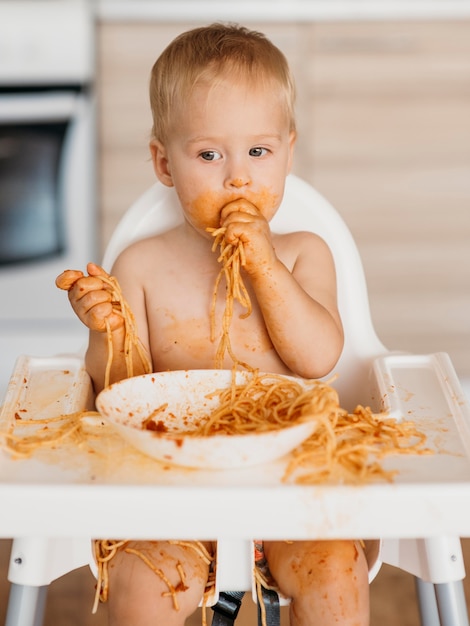 Petit garçon faisant un désordre avec des pâtes seul