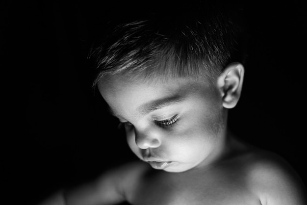 Petit garçon sur fond noir avec de la lumière se reflétant sur son visage