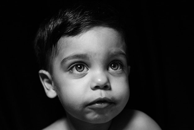 Photo gratuite petit garçon sur fond noir avec de la lumière se reflétant sur son visage