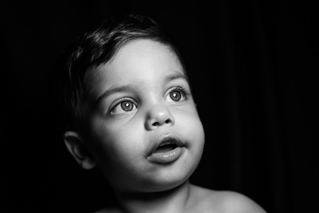 Petit garçon sur fond noir avec de la lumière se reflétant sur son visage