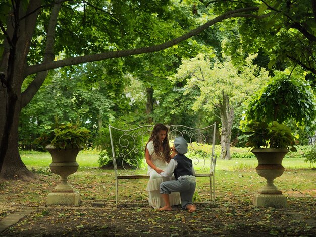 Petit garçon à genoux devant une petite fille dans un jardin