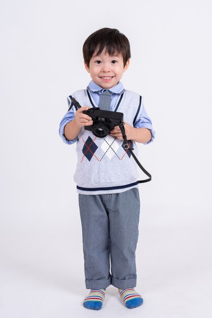 Petit garçon heureux avec caméra sur blanc