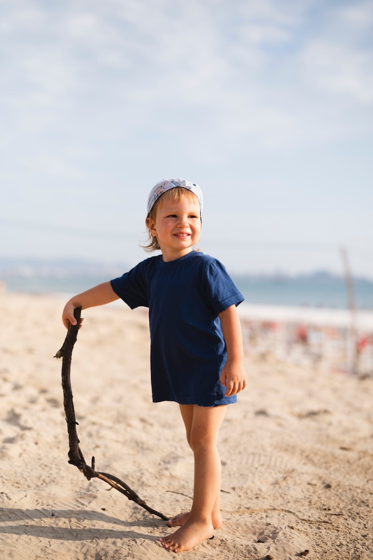 Photo gratuit petit garçon jouant avec un bâton à la plage