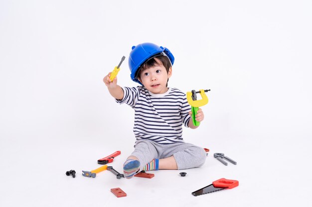 Petit garçon jouant avec des engins de chantier sur blanc