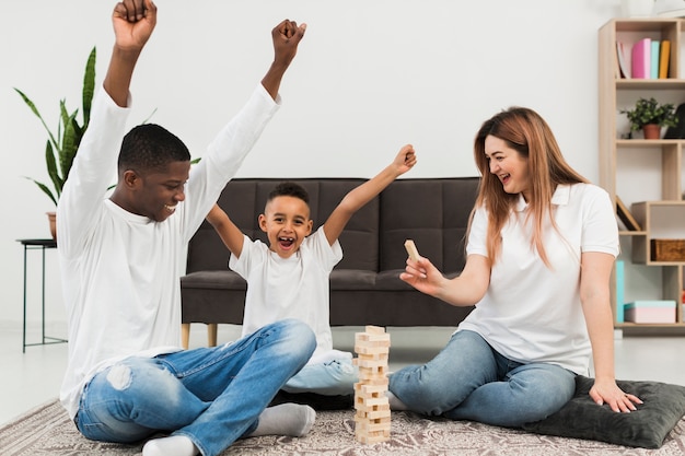 Petit garçon jouant à un jeu avec ses parents à l'intérieur