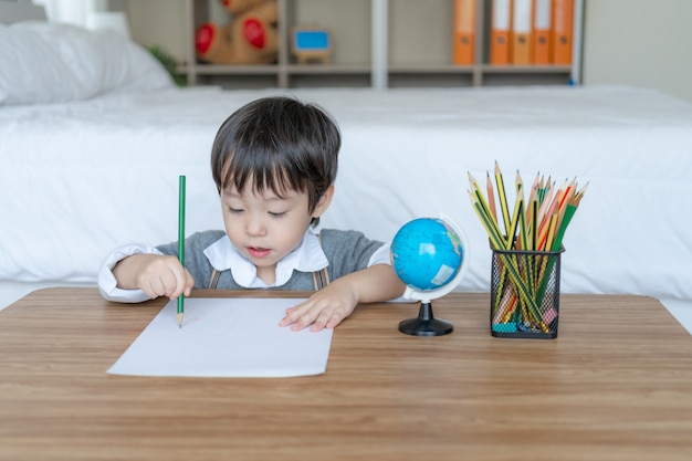 Petit garçon joyeux avec crayon couleur sur papier blanc