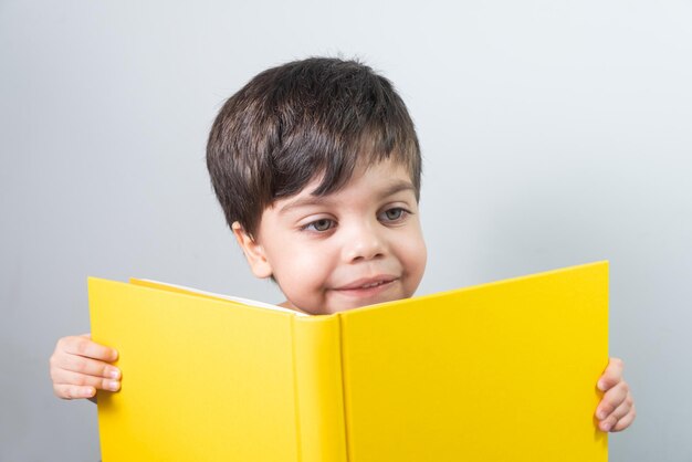 Petit garçon lisant un livre jaune