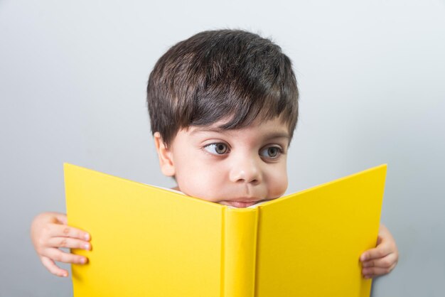 Petit garçon lisant un livre jaune