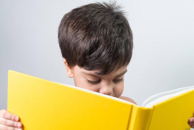 Petit garçon lisant un livre jaune