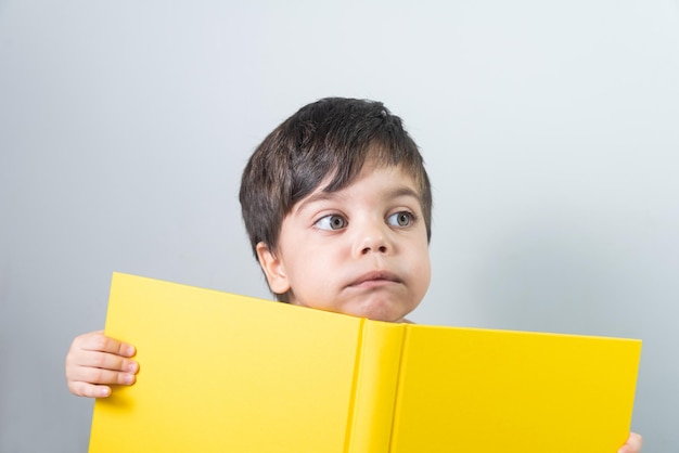 Petit garçon lisant un livre jaune