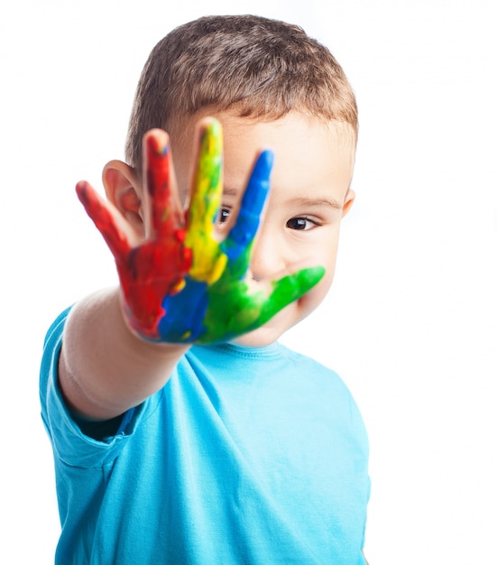 Photo gratuite petit garçon avec une main pleine de peinture couvrant son visage
