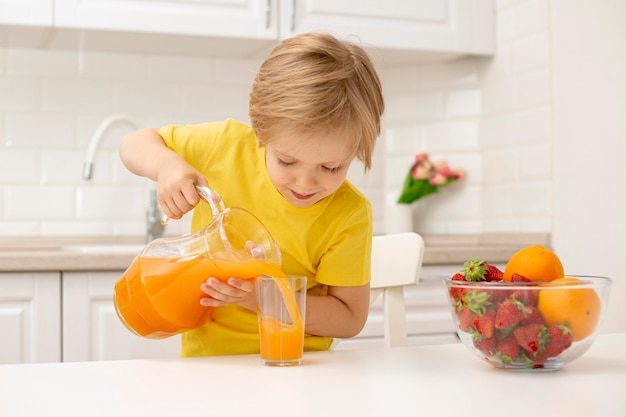 Petit garçon à la maison, verser du jus