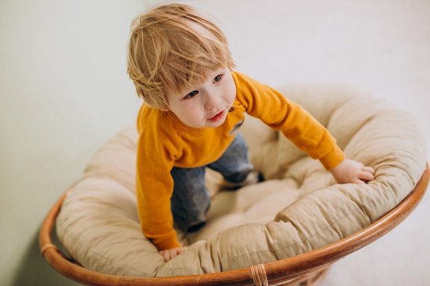 Petit garçon mignon assis sur une chaise