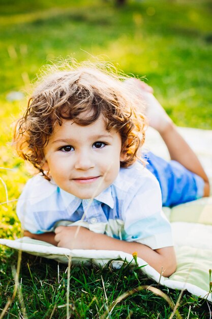 Petit garçon mignon couché sur une couverture dans le parc