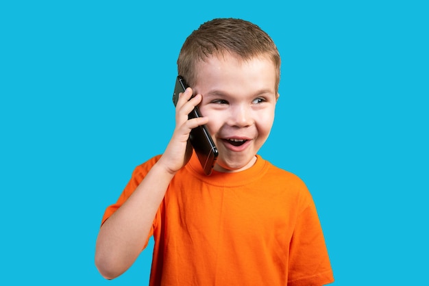 Petit garçon parlant au téléphone exprimant sa surprise. isolé sur fond bleu. pour n'importe quel but.