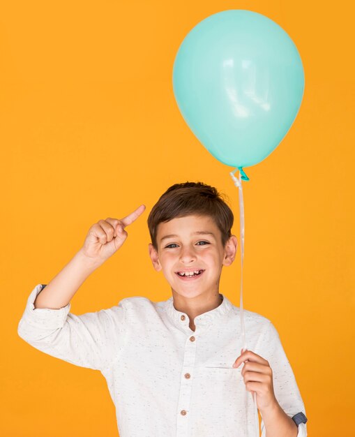 Petit garçon pointant vers son ballon bleu