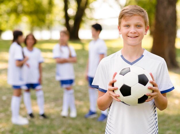 Petit garçon posant avec un ballon de football à l'extérieur