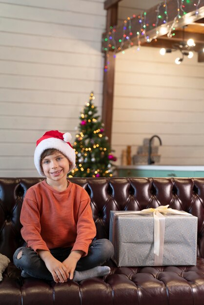 Petit garçon posant à côté d'un cadeau de Noël