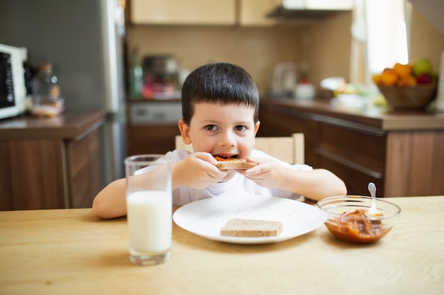 Photo gratuite petit garçon prenant son petit déjeuner à la maison