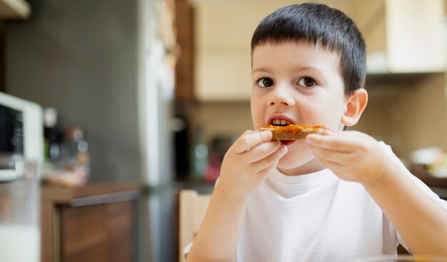 Petit garçon prend une collation à la maison