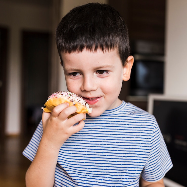 Photo gratuit petit garçon profitant de doughnout à la maison