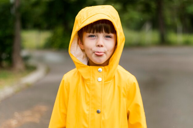 Petit garçon avec sa langue portant un manteau de pluie