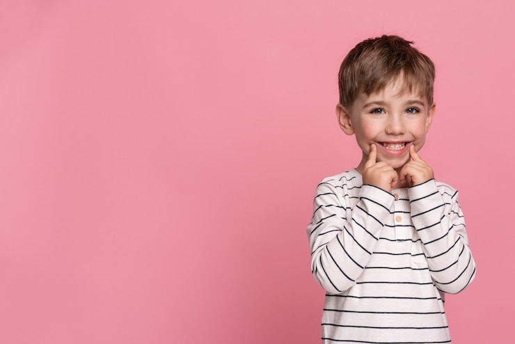 Photo gratuit le petit garçon souriant isolé sur le rose
