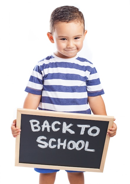 Photo gratuite petit garçon avec un tableau noir avec le message «retour à l'école